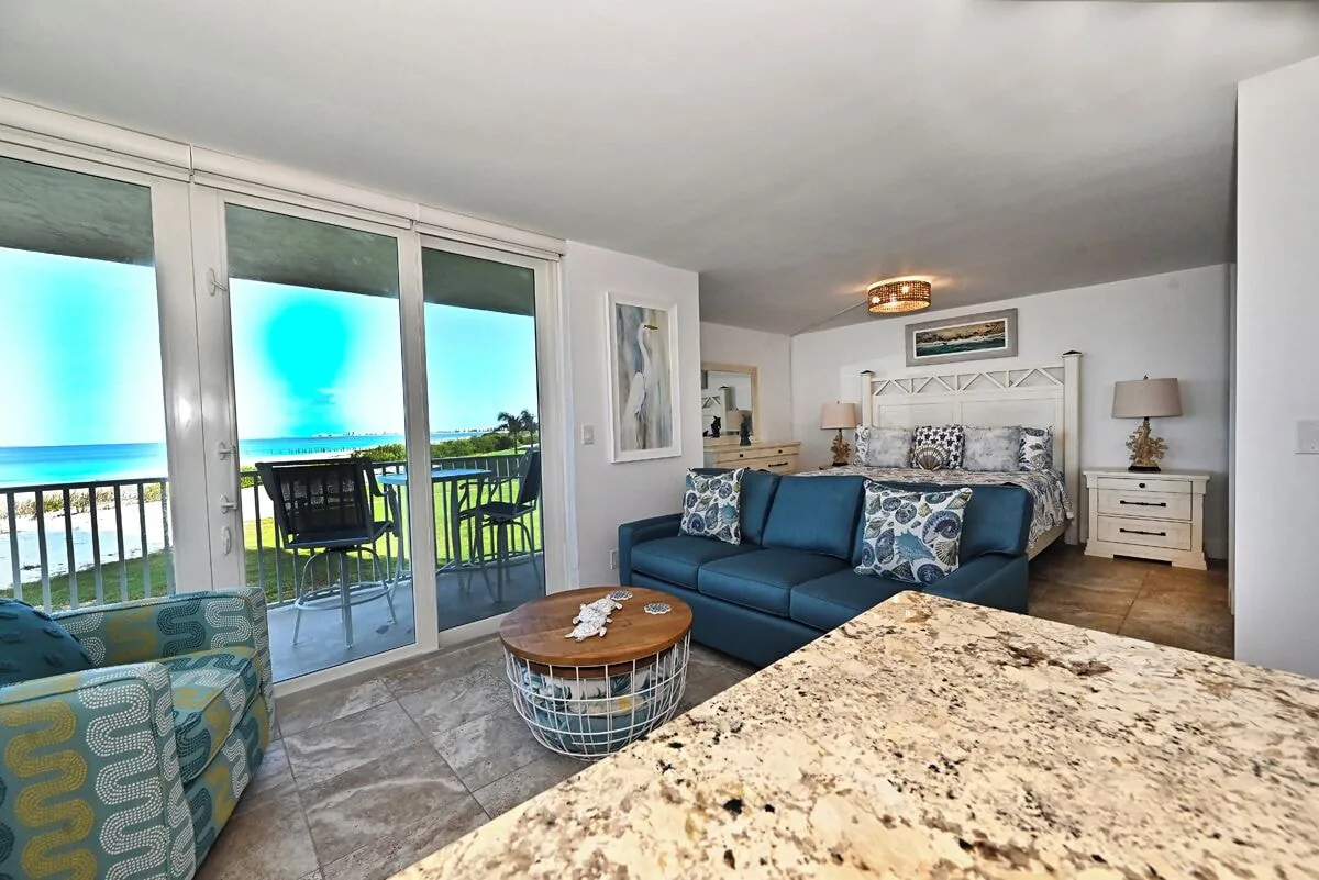 Living area with balcony window, sofa, and queen sleeper sofa at Beachfront Haven