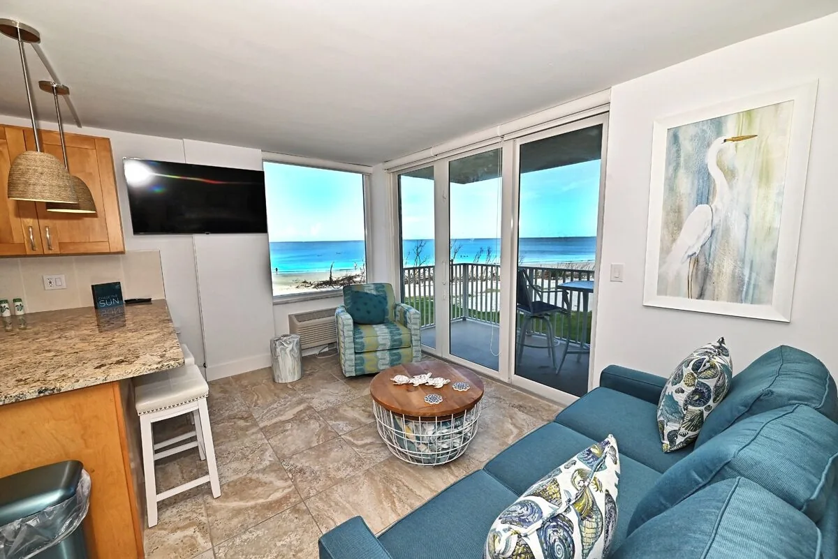 Open-concept living room with Gulf views and balcony access