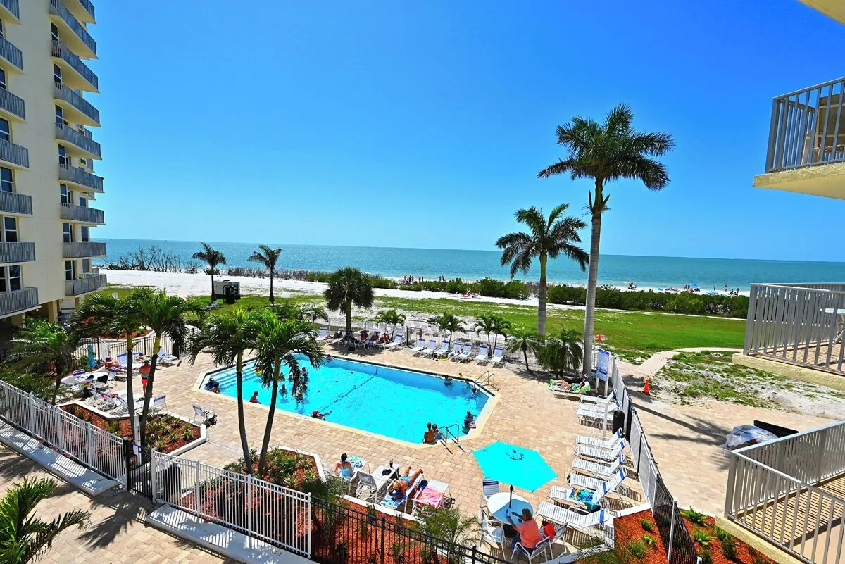 Heated pool deck with loungers and Gulf beach view